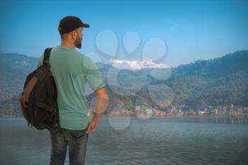 tourist traveler with a backpack stands on the background of the Himalayan mountains
