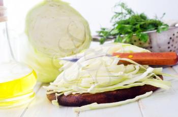 Raw cabbage and knife on the wooden board