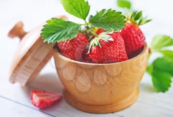 strawberry in wooden bowl and on a table