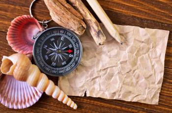sea shell, compass and note on a table