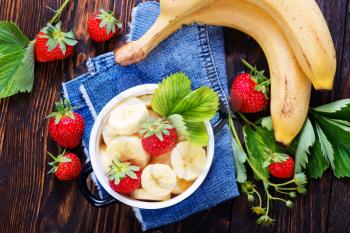 strawberry with bananas in bowl and on a table
