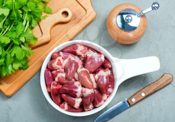 raw chicken hearts in bowl and on a table