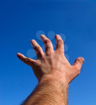 A hand with fingers spread against the blue sky