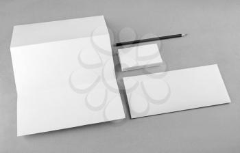 Photo of blank stationery set on gray background. Mock-up for branding identity. For design presentations and portfolios. Grayscale image.