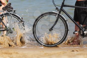 Sea wave splashing on the wheels of two bikes on the beach. Shallow depth of field.