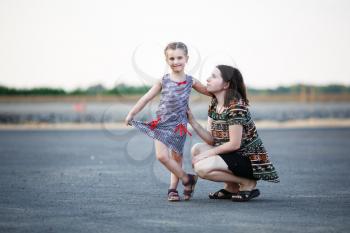 Happy family. Mother and little daughter posing for a photo on a background of asphalt road. Shallow depth of field. Selective focus.