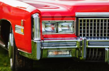 Close-up fragment of red vintage car. Red retro car. Headlights of vintage car. Shallow depth of field. Selective focus.