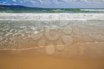 Surf on a sandy beach. Wet sand. Focus on foreground.