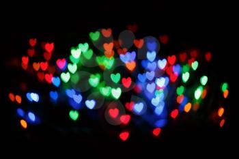 Bright colorful heart bokeh background. Multicolored blurry hearts on a black background.