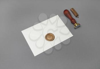 Vintage letter envelope with golden wax seal, stamp and spoon on gray paper background. Mock-up for your design. Flat lay.
