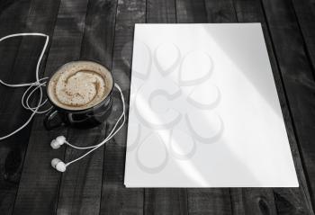 Blank stationery template on wood table background. Letterhead, coffee cup and headphones. Responsive design template.