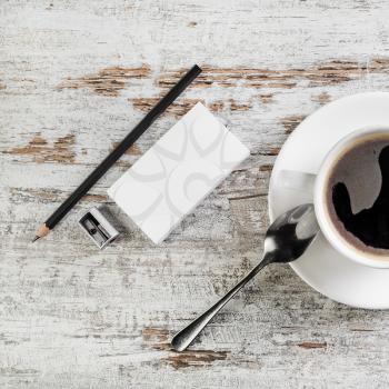 Still life with bank business cards, coffee cup, spoon, pencil and sharpener on wooden background.
