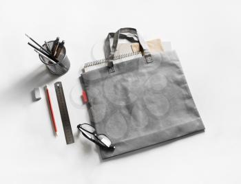 Gray shopping canvas bag and stationery on white paper background.