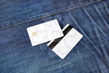 Two bank plastic bank cards on denim background. White credit cards. Front and back view.