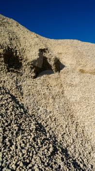 Vertical vivid heap of rock with vibrant blue sky background