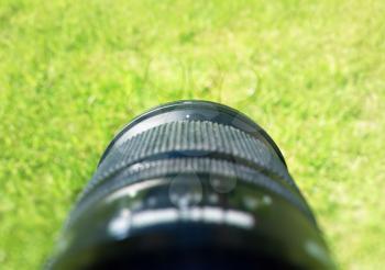 Photography lens pointed on fresh green summer grass background