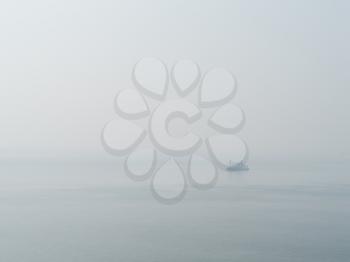 Horizontal sparse pale lonely ship in white ocean background backdrop