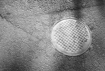 Black and white manhole in asphalt background