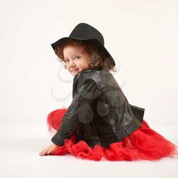Little girl with black hat sitting and smiling