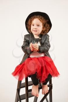 Little girl with black hat sitting and asks a toy