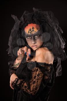 Halloween devil's bride. Portrait of young woman in dark artistic image with scary makeup, veil and terrible picture on her forehead.