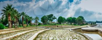 A path in a small park with a viewing platform on top of the white Pamukkale mountain near travertines on a summer morning.