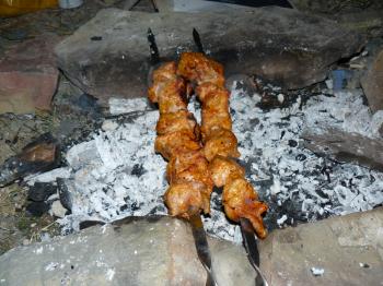 Shish kebab on a skewer. Preparation of a shish kebab in house conditions on a fire in the yard.
