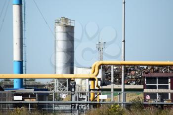 Big plant for processing scrap metal. Huge factory old metal refiner. Blue roof of the factory building. Exhaust pipes, radiators, cooling industrial units as well as office buildings.