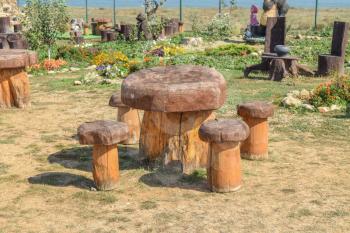 Table and chair in the shape of mushrooms. Outdoor wood furniture. Stumps with back seating. Wooden furniture for the street.