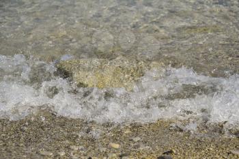Sea waves run ashore, bubbling and stone covering.