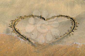 Heart drawn on the beach sand. heart symbol on the sand washed by the sea wave.