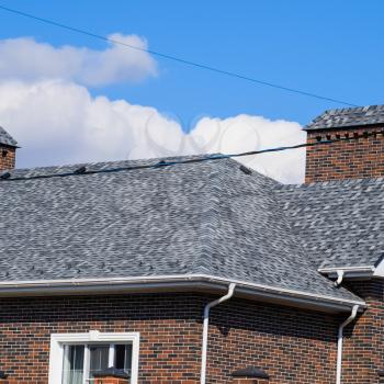 Asphalt shingle. Decorative bitumen shingles on the roof of a brick house