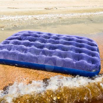 Blue inflatable mattress swimming in the pond. An inflatable mattress on the beach.