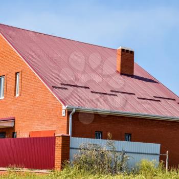 Detached house with a roof made of steel sheets. Roof metal sheets. Modern types of roofing materials.