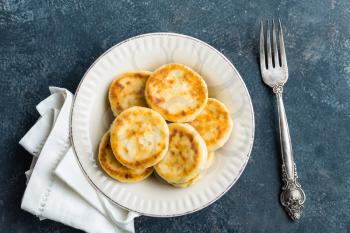 Frying homemade cottage cheese pancakes, syrniki on white plate