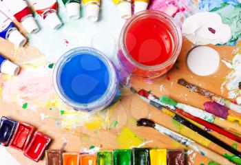 Multicolored paints, brushes, palette, water. Desk, workplace artist. . Drawing concept.backgrounds art. View from above, flat