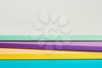 A stack of color notebooks, yellow, purple, green. Copy space