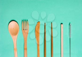 Natural, ecological, Organic wooden fork, spoon, cutlery on a green background. Concept zero waste, environmental pollution.