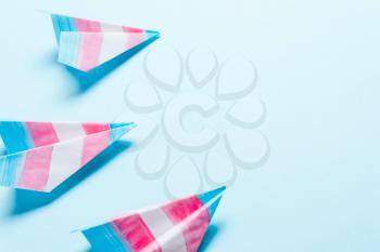 Paper airplane in transgender flag on a blue background