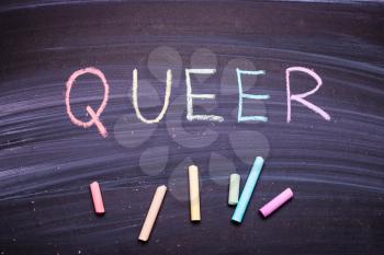  word Queer on a chalkboard, a symbol of LGBT, the colors of the rainbow
