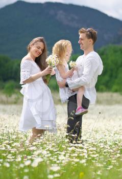 Happy family on big camomile mountain meadow. Emotional, love and care scene.