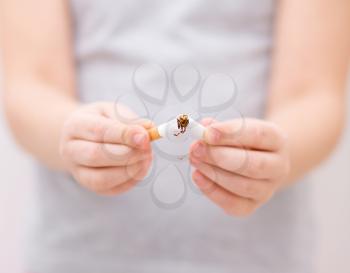 Young girl is breaking a cigarette, quit smoking concept