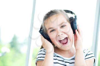 Cute girl is enjoying music using headphones and closed her eyes