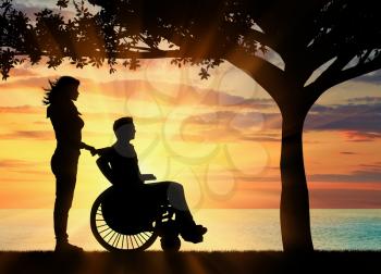 Concept of disability and disease. Silhouette of disabled person with a guardian on the sea sunset under the branches of a tree