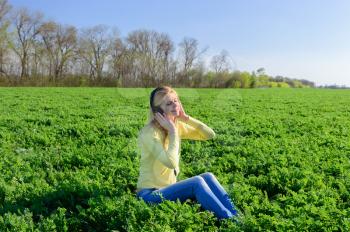 Concept of music. Young woman with headphones listening to music on meadow