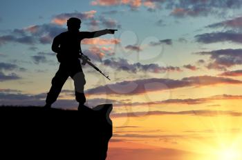 Silhouette of soldier with a gun on a background of sunset