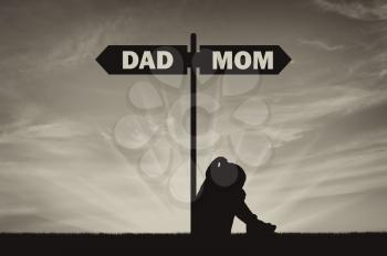 Divorce in the family. Silhouette of a sad baby girl crying sitting near the signpost road dad or mom. The concept of divorce and division of children