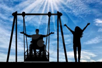 Silhouette of happy couple, man in wheelchair for disabled person on adaptive swing and healthy woman nearby. The concept of the lifestyle of people with disabilities