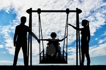Silhouette of a happy child is a disabled person in a wheelchair on an adaptive swing. Mom and Dad swing it. The concept of the lifestyle of children with disabilities