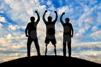 Support and help people with disabilities the concept. Happy disabled man with a prosthetic leg standing and his friends at sunset on top of the hill